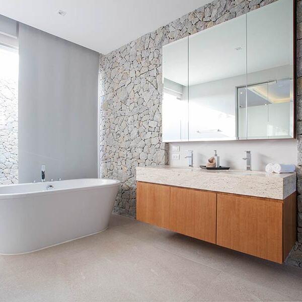 Badmöbel nach Maß vom Schreiner bestehend aus weißer freistehender Badewanne neben Waschbeckenunterschrank aus Holz mit Doppelwaschbecken und Spiegel