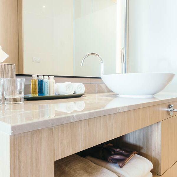 Waschbeckenunterschrank nach Maß aus hellem Holz unter weißem Waschbecken