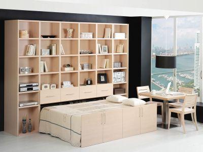 Ein elegantes Wohnzimmer mit einem großen, hellen Regalsystem und einem vollständig ausgezogenen Schrankbett. Daneben befindet sich ein Essbereich mit Holztisch und Stühlen. Ein großes Fenster bietet einen spektakulären Blick au