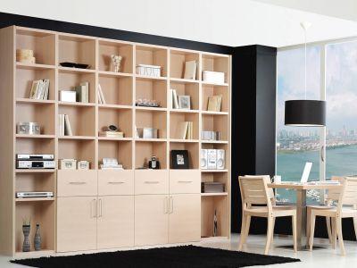 Modern gestaltetes Wohnzimmer mit einem umfangreichen, maßgefertigten Regalsystem in heller Holzoptik, gefüllt mit Büchern und Dekorationsartikeln. Ein Essbereich mit Holztisch und Stühlen befindet sich neben dem Regal, mit Blick auf