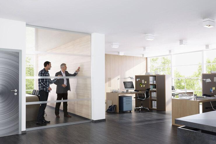 Impression eines Büros mit abgeschlossenem Raum mit Glaswand und offener Bürogestaltung.